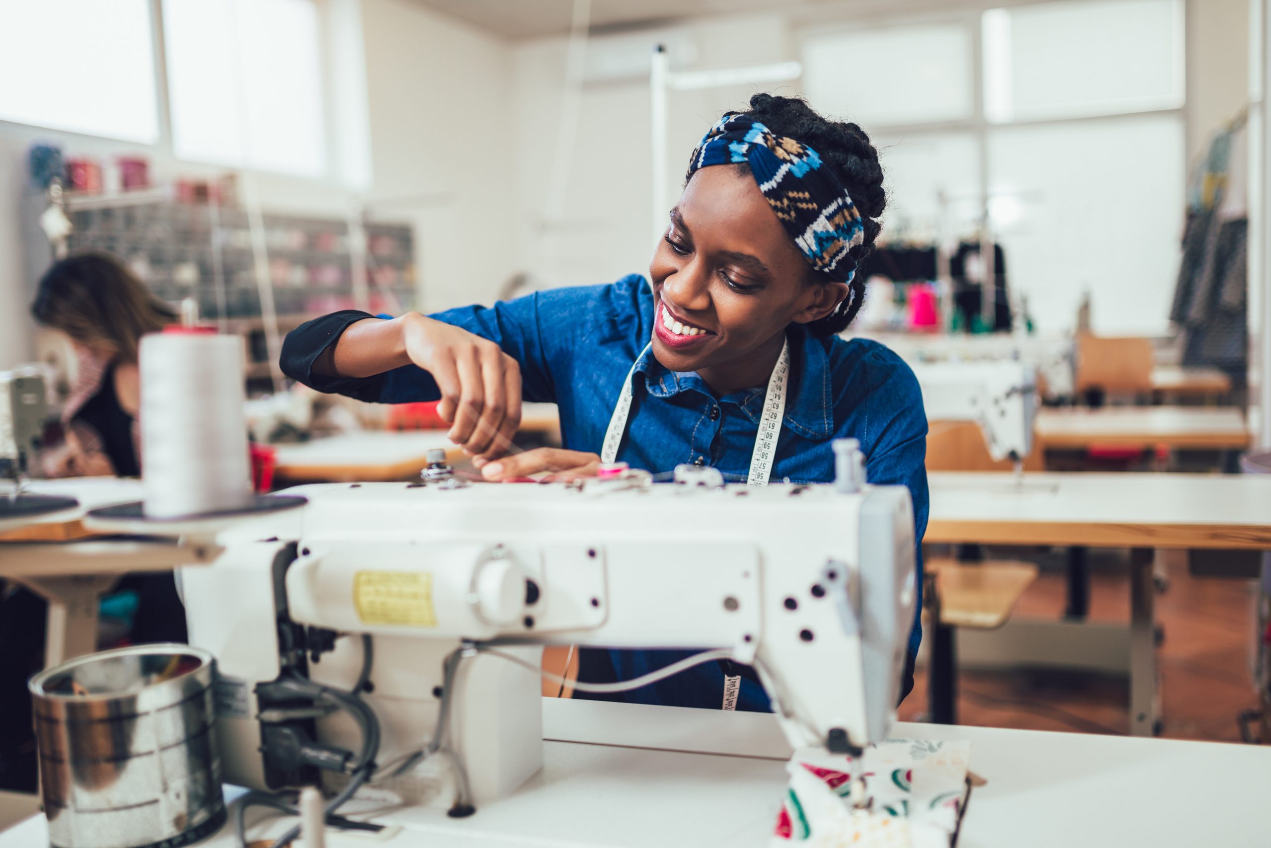 Young african textile worker sewing on production line. Dressmak